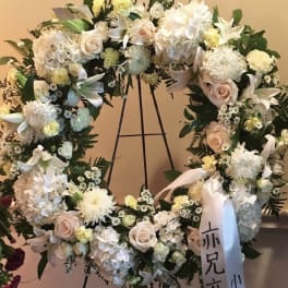 Large white floral wreath with pale pink roses on a stand