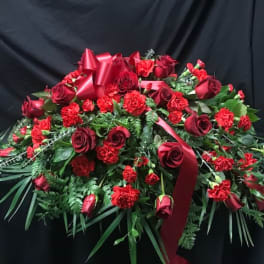 Large red rose and carnation arrangement with ribbon on a black backdrop