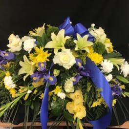 Large floral spray with white, yellow, and purple flowers and blue ribbon