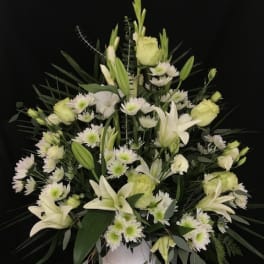 White lilies and daisies arranged in a white vase