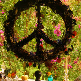 Large wreath with dark leaves hanging over a table in a garden setting