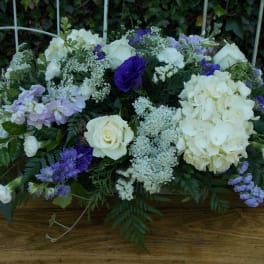 Low floral arrangement with white roses, hydrangeas, and purple blooms