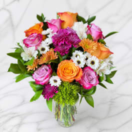 Mixed bouquet of pink and orange roses with white daisies in a glass vase