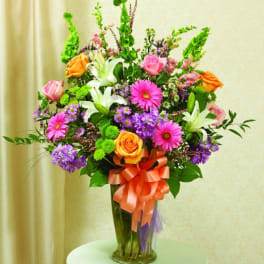 Colorful mixed bouquet in a tall glass vase with a ribbon bow