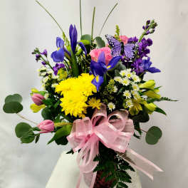 Colorful bouquet with purple irises, yellow chrysanthemums, pink tulips, and a pink ribbon