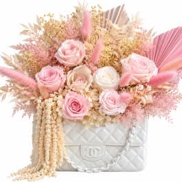 Pink and cream roses arranged in a white quilted handbag