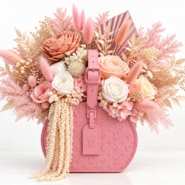 Pink floral arrangement in a pink designer handbag-shaped container