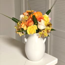 Bouquet of orange, yellow, and white roses in a white vase