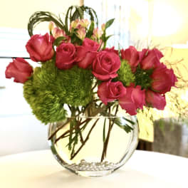 Pink roses in a round glass vase with green pom-pom flowers