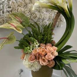Floral arrangement with white roses, peach roses, calla lilies, and anthuriums in a vase