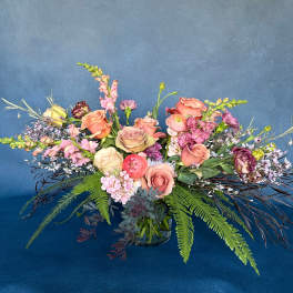 Mixed bouquet of pink and peach flowers in a glass vase