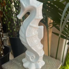 White ceramic seahorse figurine on a textured pedestal
