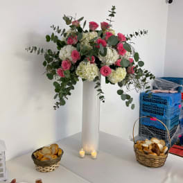 Tall floral arrangement of pink roses and white hydrangeas in a white vase