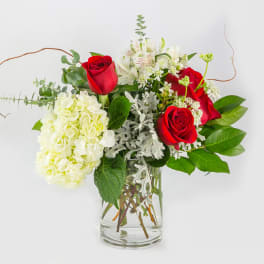 Red roses and white hydrangea in a clear glass vase