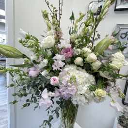Tall bouquet of white and pale pink flowers in a clear glass vase