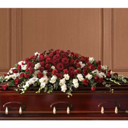 Red and white floral casket spray on a wooden casket