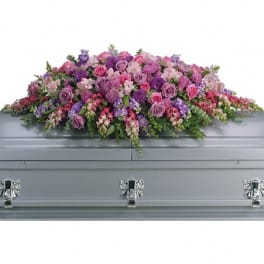Pink and purple floral casket spray on a gray casket