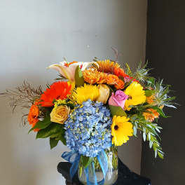 Colorful mixed bouquet in a glass vase with blue ribbon