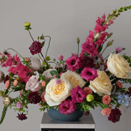 Mixed bouquet of pink and cream flowers in a blue vase