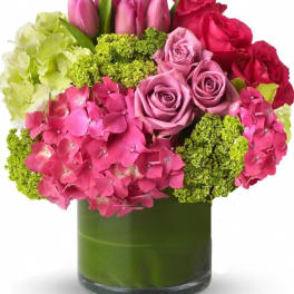 Pink and red roses with hydrangeas in a green glass vase
