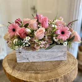 Pink roses and gerbera daisies arranged in a rustic wooden box