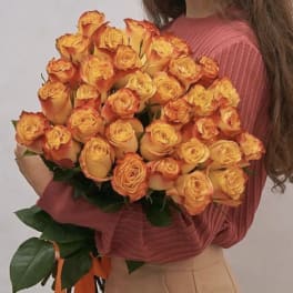 Woman holding a large bouquet of orange-yellow roses