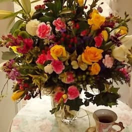 Large mixed bouquet in a clear glass vase with yellow, pink, and white flowers
