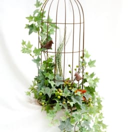 Ivy draped over a tall wire birdcage with small bird accents