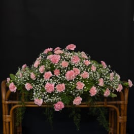 Pink carnations arranged in a wicker basket with baby's breath