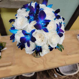 White rose bouquet with vivid blue-purple orchids in a small vase