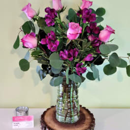 Pink roses and purple flowers arranged in a glass vase