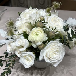 White rose bouquet in a white vase with green foliage