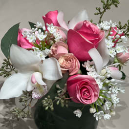Pink roses and white orchids in a dark vase