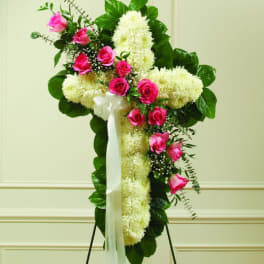Pink roses and white flowers arranged in a cross on a stand