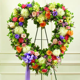 Heart-shaped floral wreath with roses and chrysanthemums on an easel