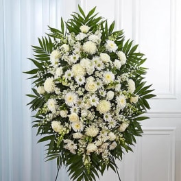 Large white floral standing spray with palm leaves on an easel