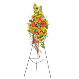 Tall floral standing spray with yellow and orange flowers on an easel
