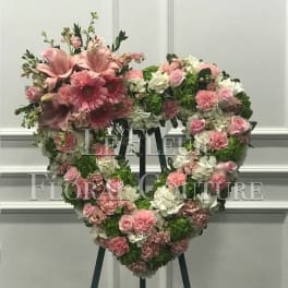 Heart-shaped floral wreath with pink and white flowers on an easel
