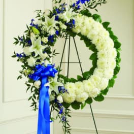 White floral wreath with blue ribbon on a stand