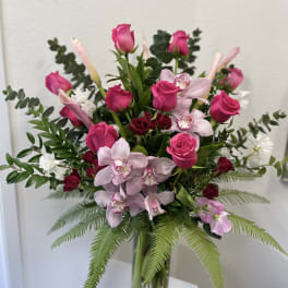 Pink roses and orchids arranged in a clear glass vase