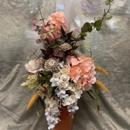 Tall floral arrangement in an orange vase with pink and white blooms