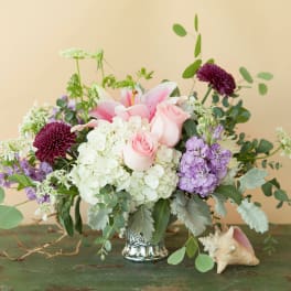 Pink lilies and roses in a silver vase with white and purple flowers