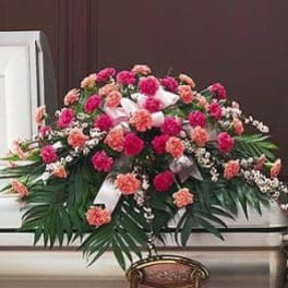Pink and peach carnation casket spray with white ribbon