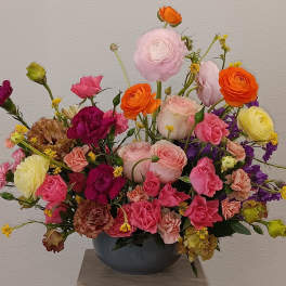 Mixed bouquet in a dark vase with pink, orange, yellow, and purple flowers