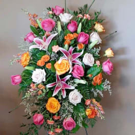 Standing floral spray with pink, white, and orange roses and lilies