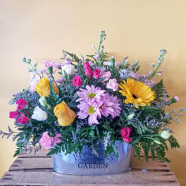 Mixed bouquet in a metal container with pink, yellow, white, and lavender flowers