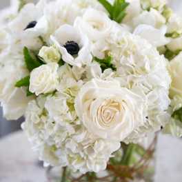 White roses and hydrangeas arranged in a clear glass vase.