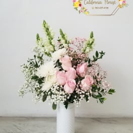 Pink roses and white flowers arranged in a white vase