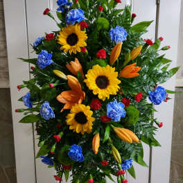 Standing floral spray with sunflowers, lilies, and carnations in bright colors