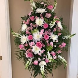 Standing floral spray with pink and white flowers on a black easel
